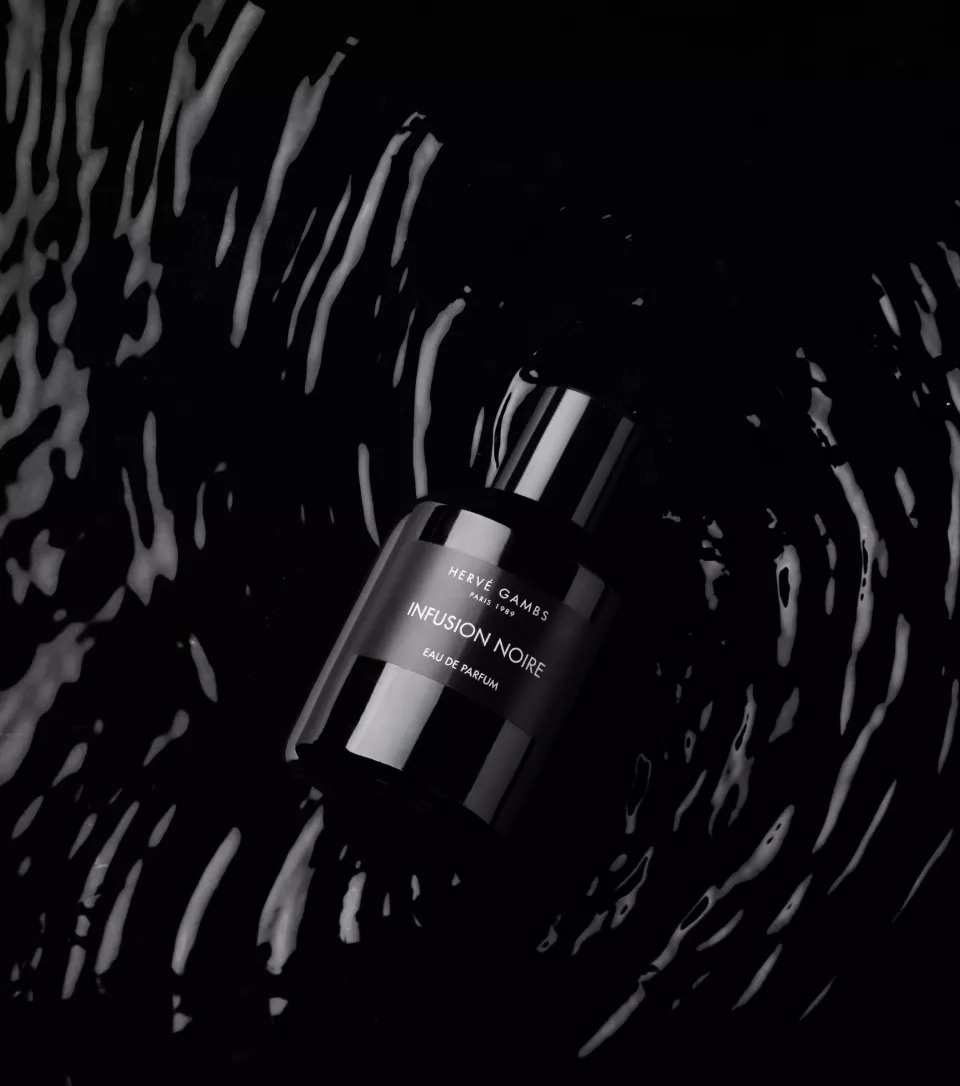 This is a masterclass in high-contrast photography. Placing a black bottle in rippling black water creates a very masculine, mysterious, and "expensive" vibe.