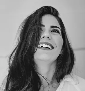 High-angle black and white shot of a woman looking up and laughing, featuring a bright, candid expression and soft lighting.